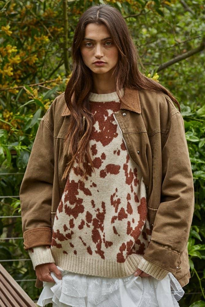 Woman in cow print sweater and brown jacket, outdoor coastal style
