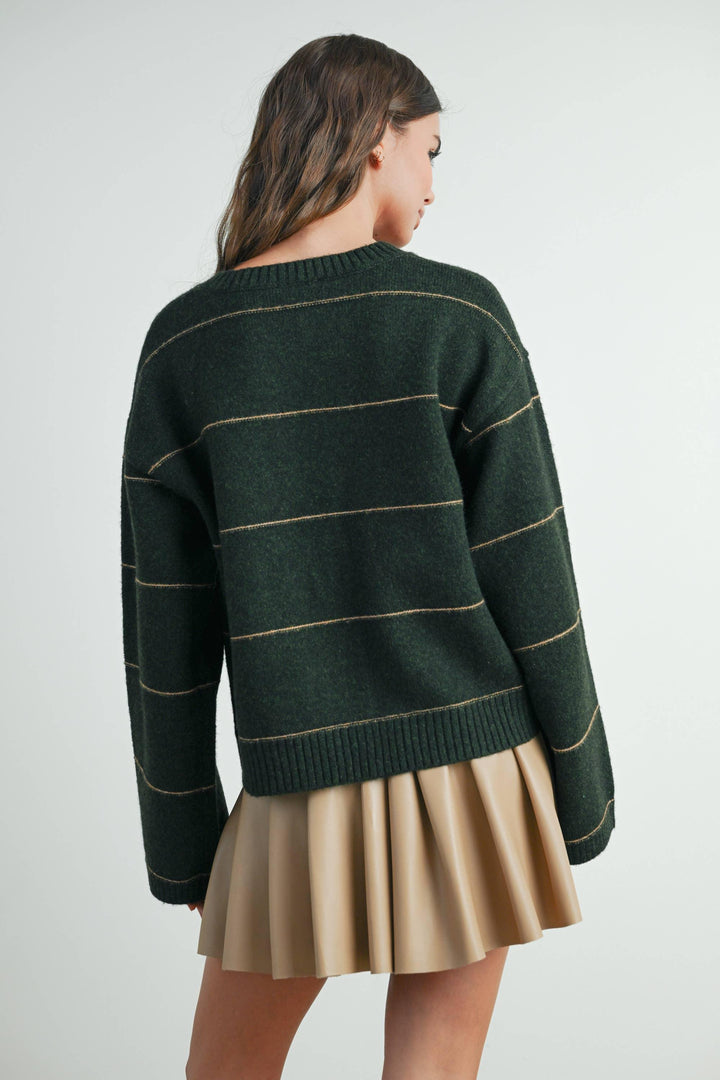 Woman wearing green striped knit sweater with tan pleated skirt, coastal style outfit