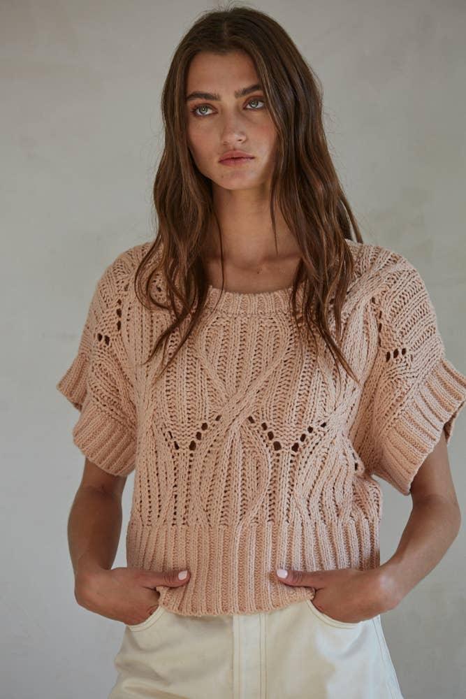 Woman wearing beige knitted short-sleeve sweater with cable knit and openwork details