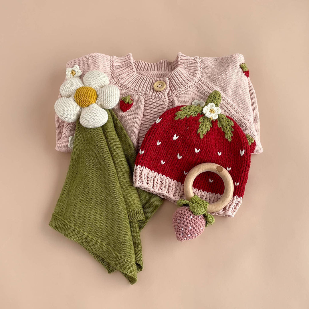 Knit baby set with strawberry hat, daisy flower, and green blanket for cozy outdoor adventures