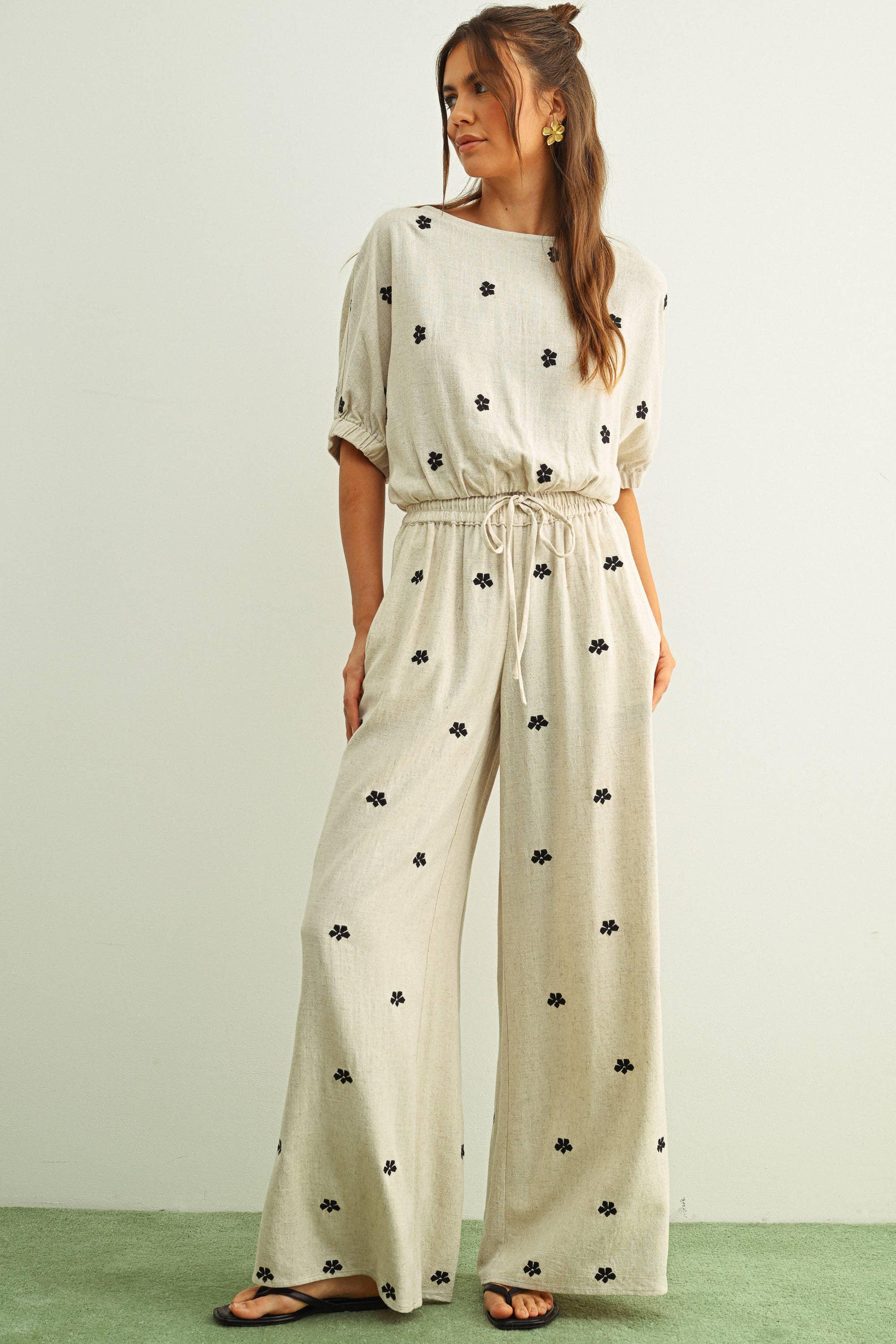 Beige floral print jumpsuit with wide legs and drawstring waist, styled with black flip flops