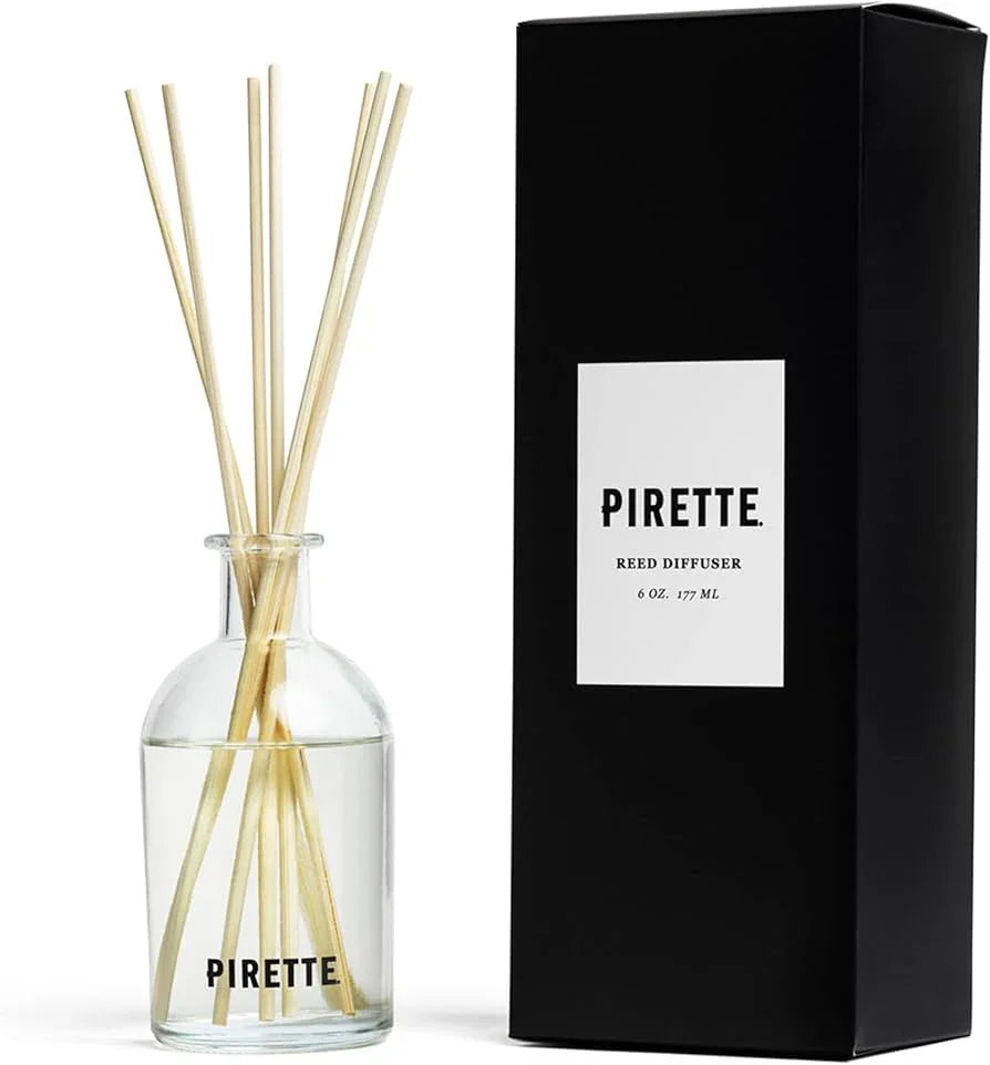 Pirette reed diffuser in clear glass bottle with natural reeds, 6 oz, next to black packaging