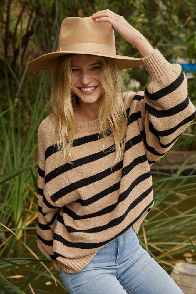 Woman in striped sweater and wide-brim hat, outdoor coastal style