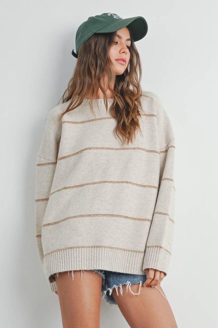 Woman in cozy striped sweater, denim shorts, and green baseball cap, casual fall outfit
