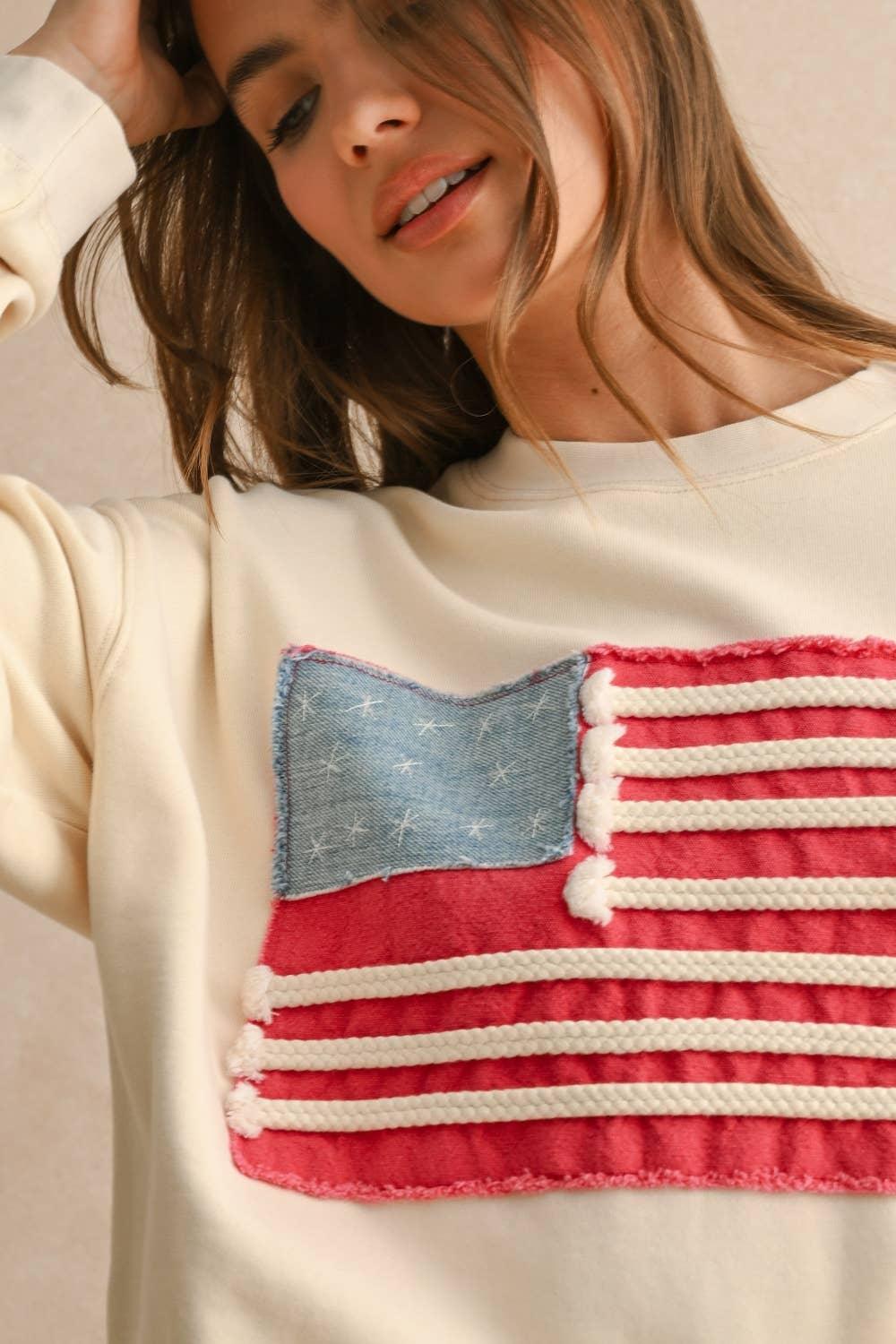 Close-up of a cream MIOU MUSE sweatshirt featuring a textured American flag patch.
