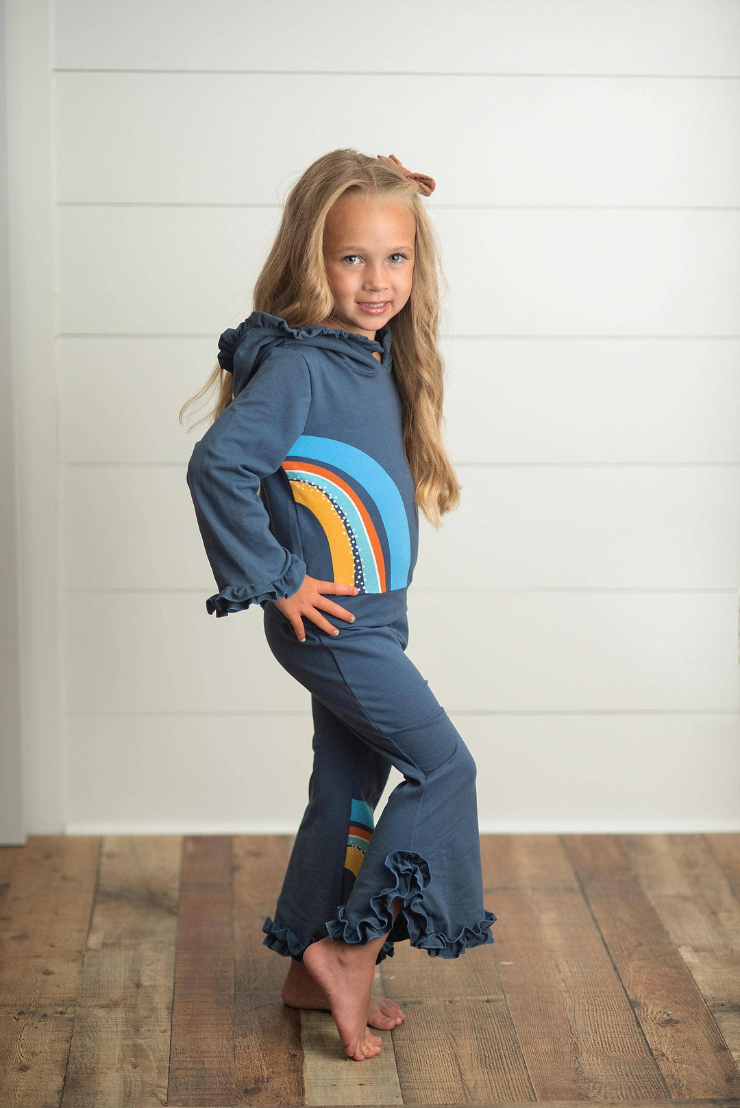 Girl in navy rainbow hoodie and ruffle pants, coastal style kids outfit