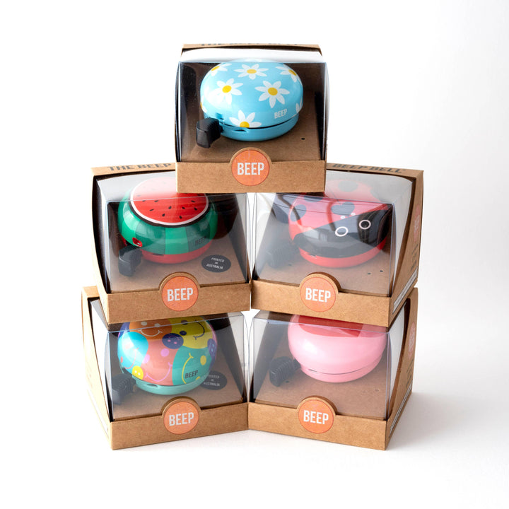 Colorful Beep bike bells in daisy, watermelon, ladybug, and smiley designs, perfect for outdoor adventures.