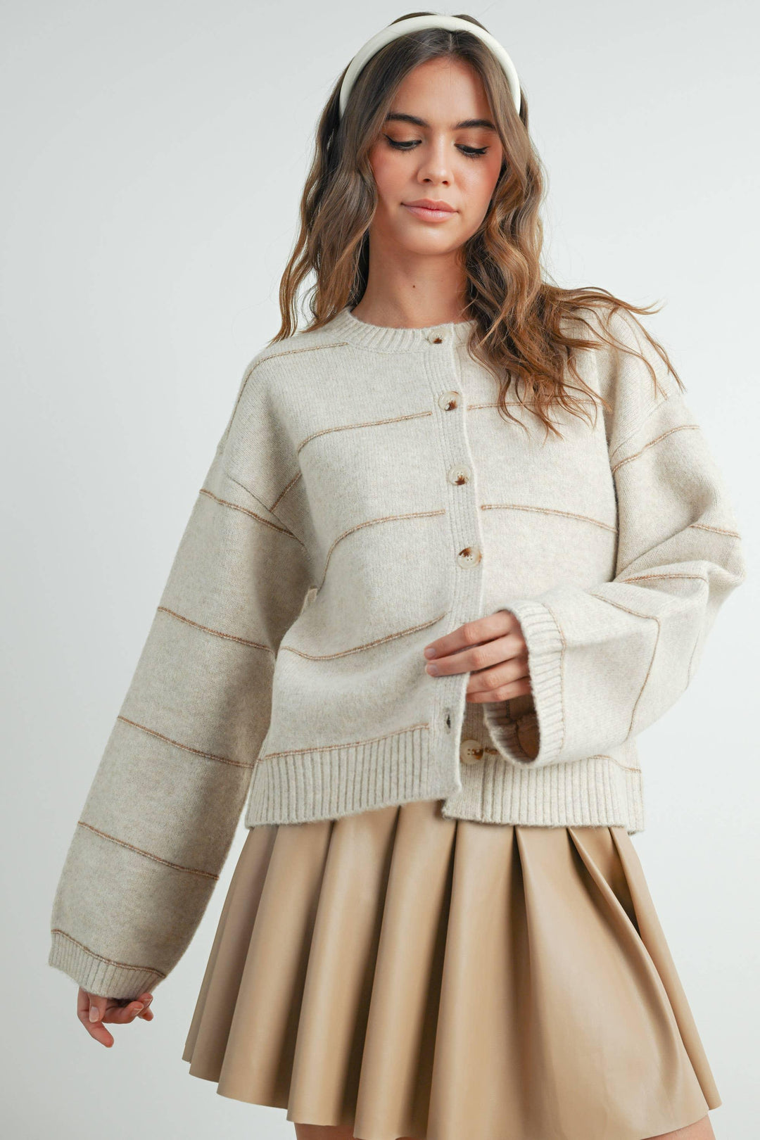 Cream button-front cardigan with contrast stitching, paired with pleated skirt and headband for coastal style