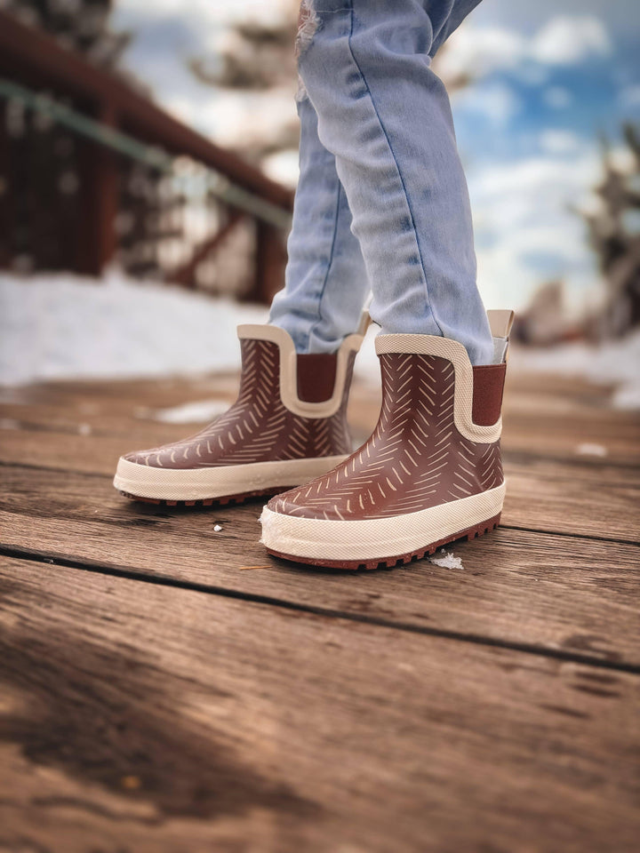 Brown herringbone rain boots on wooden deck, perfect for PNW adventures and coastal style