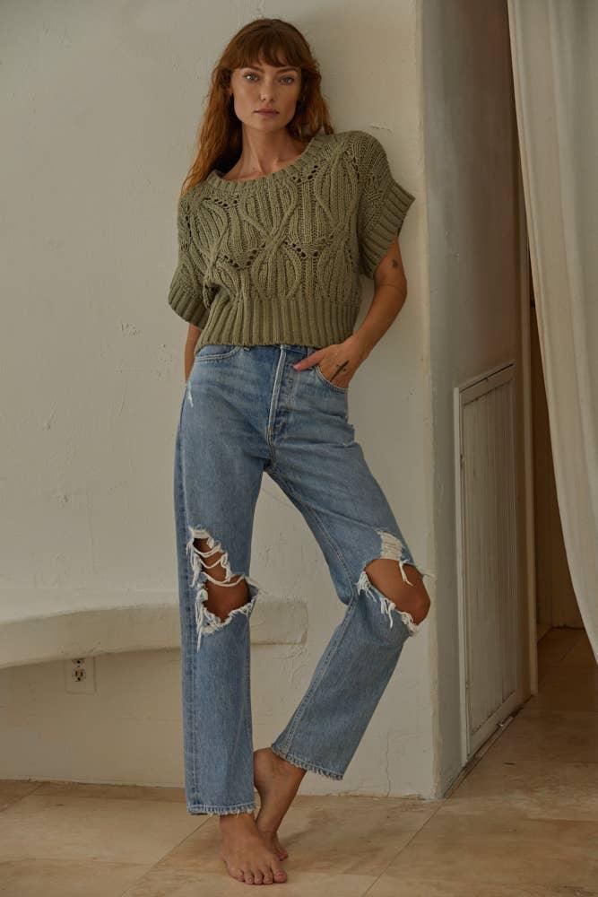 Woman in olive cable knit top and ripped blue jeans, casual summer outfit