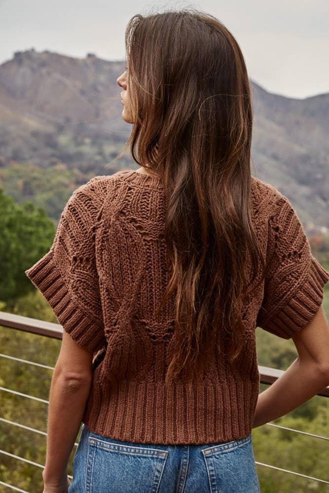 Woman in brown cable knit sweater overlooking mountain view, coastal outdoor style
