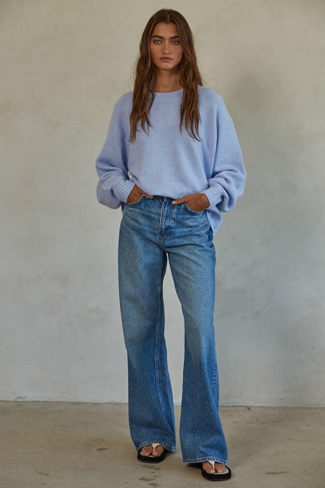 Woman in light blue sweater and wide-leg denim jeans, coastal style outfit