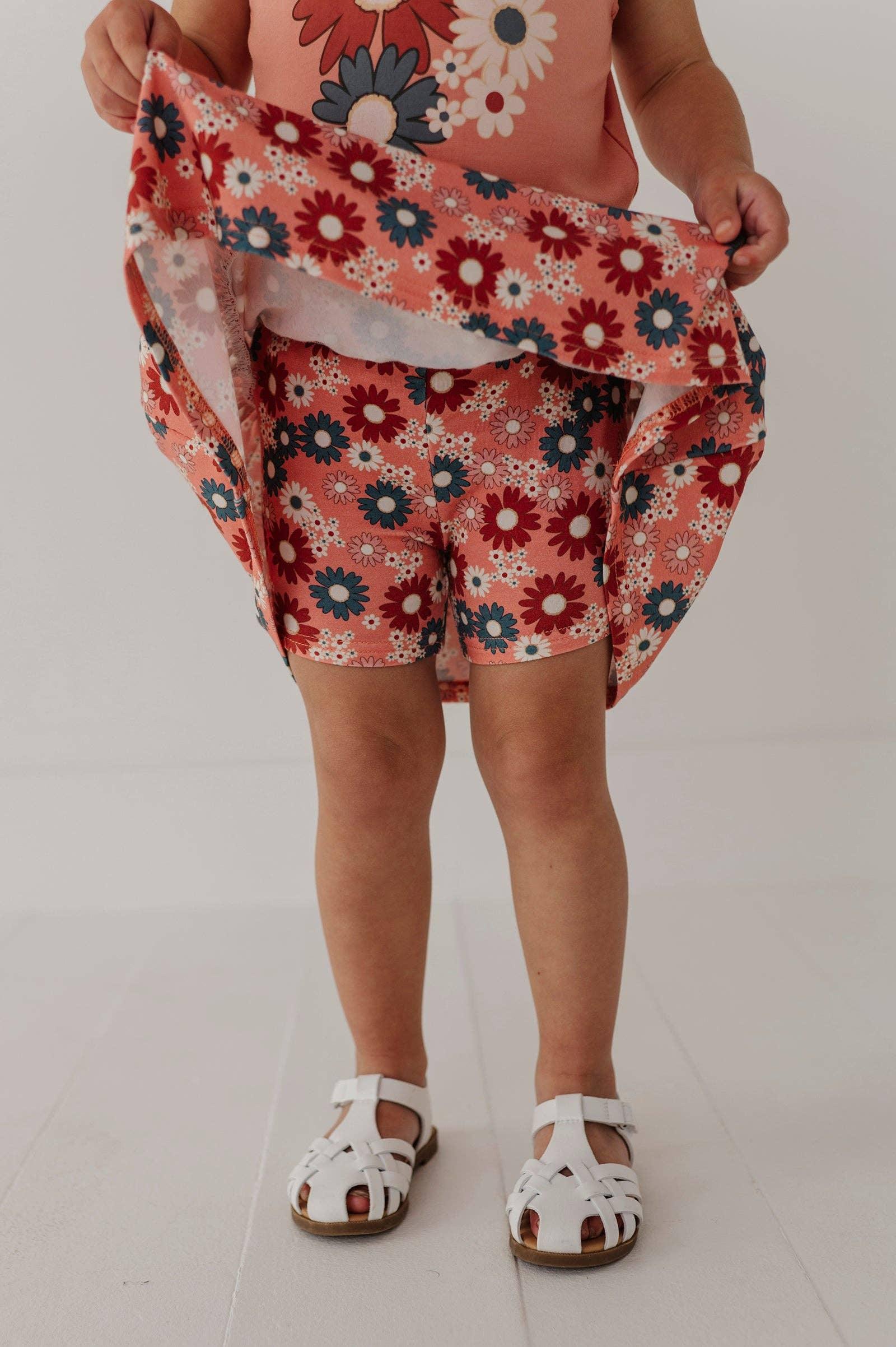 Child in floral print shorts and top with white sandals, perfect for beach days and outdoor adventures.