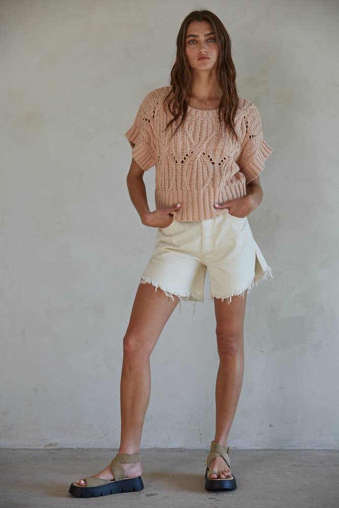 Woman in beige knit top and cream denim shorts with platform sandals