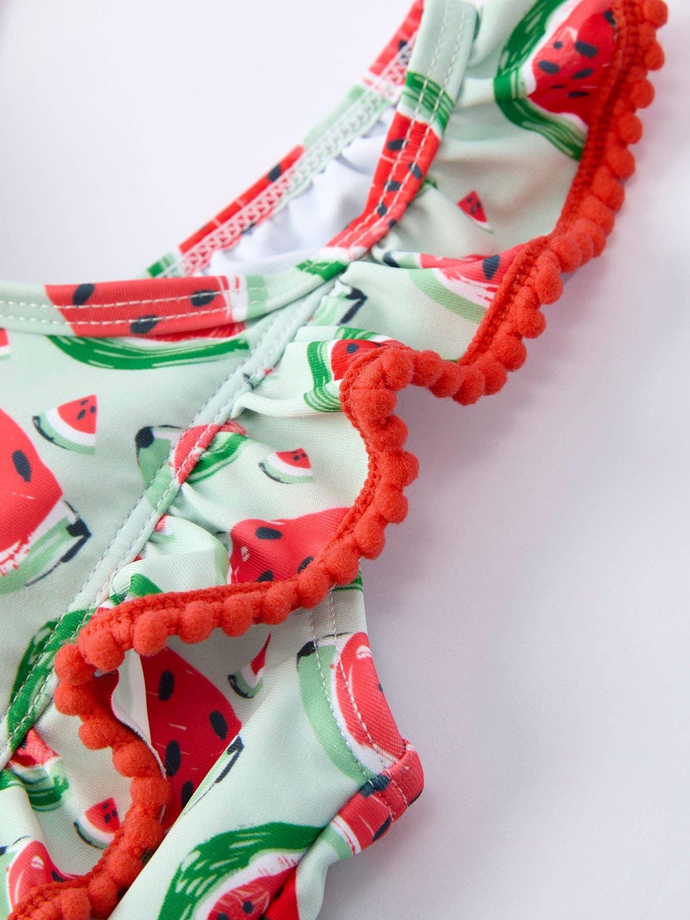 Watermelon print swimsuit with orange pom-pom trim, perfect for beach days and coastal adventures.