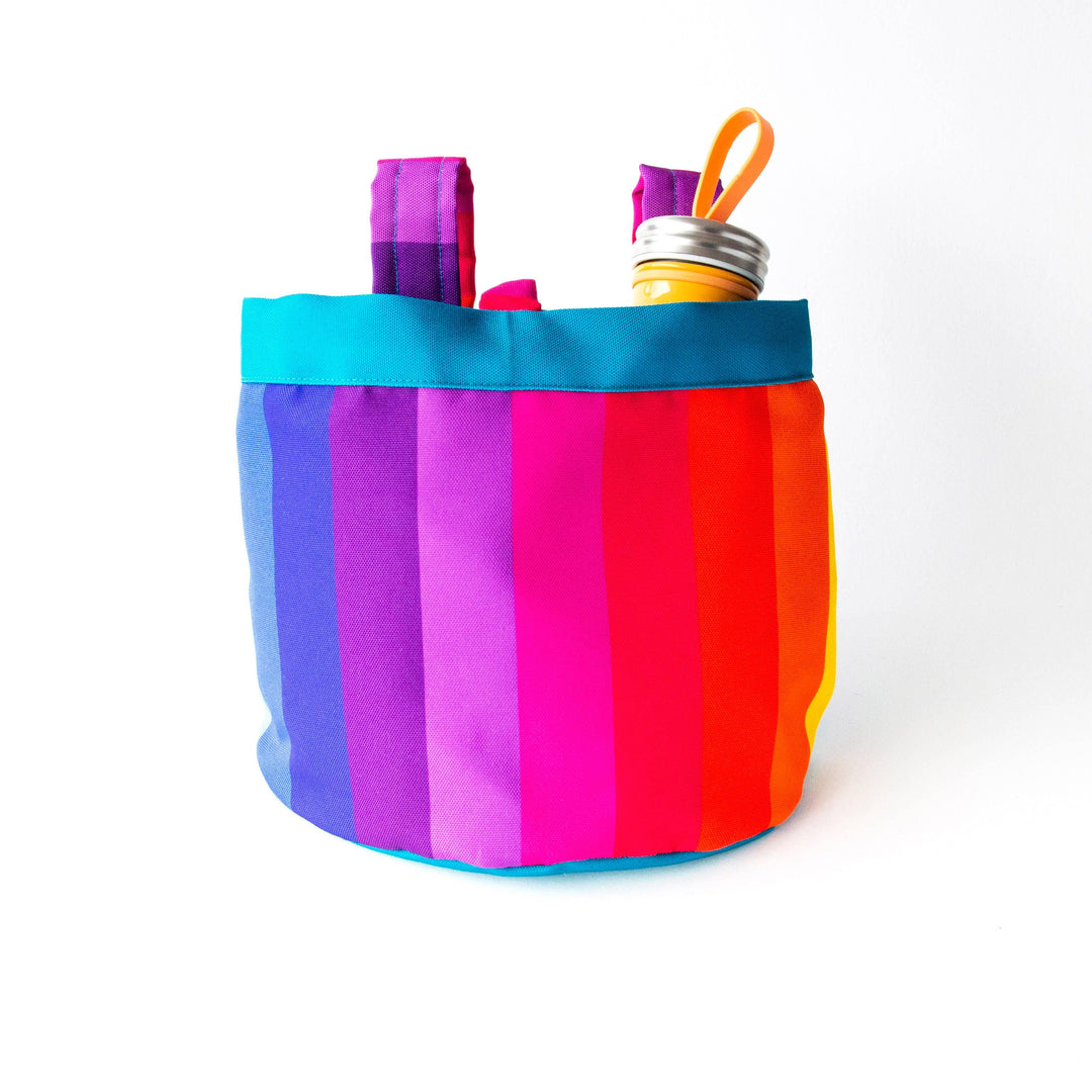 Vibrant rainbow striped tote bag with water bottle, perfect for beach days and outdoor adventures.
