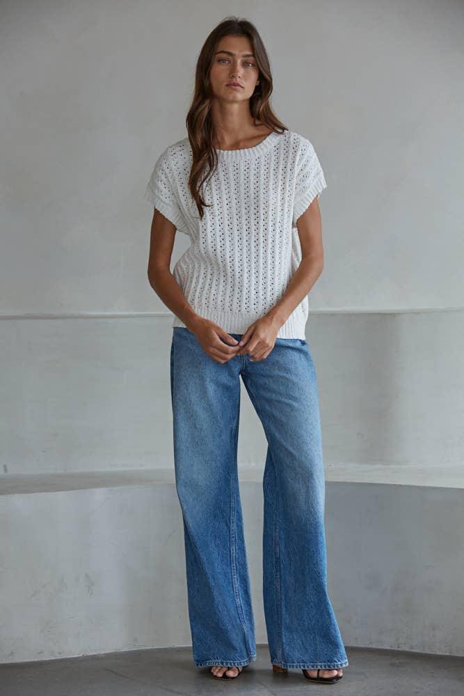 Woman in white knit top and wide-leg blue jeans, coastal casual style