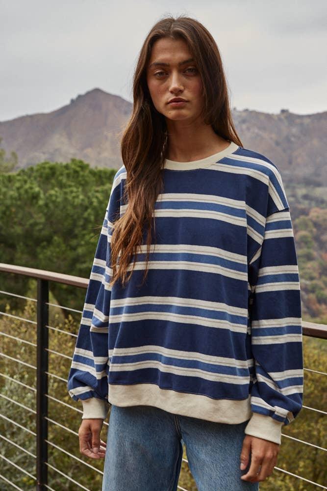 Woman in blue and white striped long sleeve sweater, mountain backdrop, coastal outdoor style
