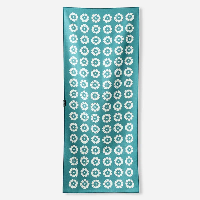 Teal beach towel with white floral pattern, perfect for coastal adventures and outdoor lifestyle gear.