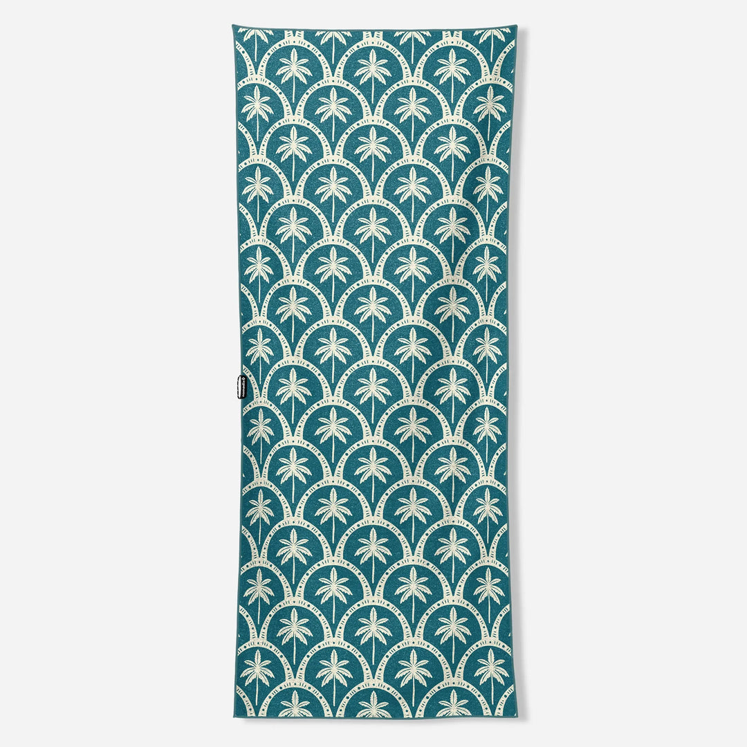 Teal beach towel with white palm tree and scallop pattern, ideal for board and bike adventures
