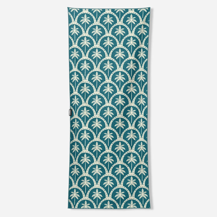 Teal beach towel with white palm tree and scallop pattern, ideal for board and bike adventures
