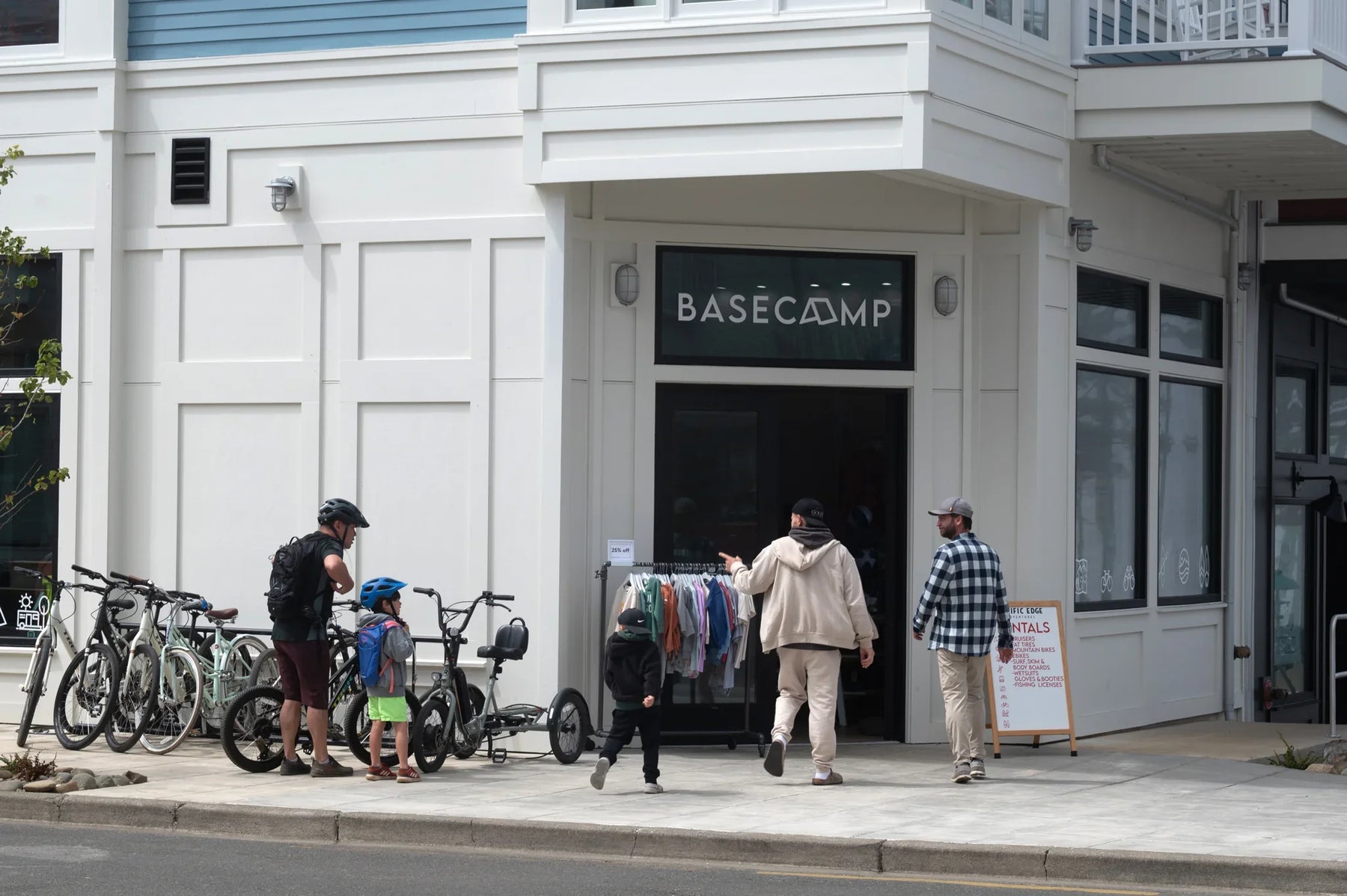 Family with bikes outside coastal outdoor gear shop, browsing apparel and rentals in Seabrook, WA