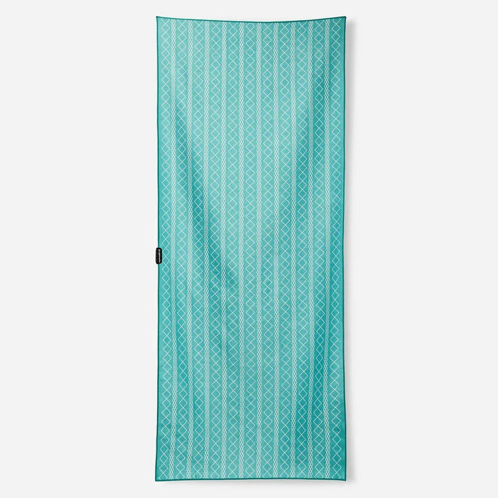 Turquoise beach towel with white geometric stripes, perfect for coastal adventures and outdoor weekends.