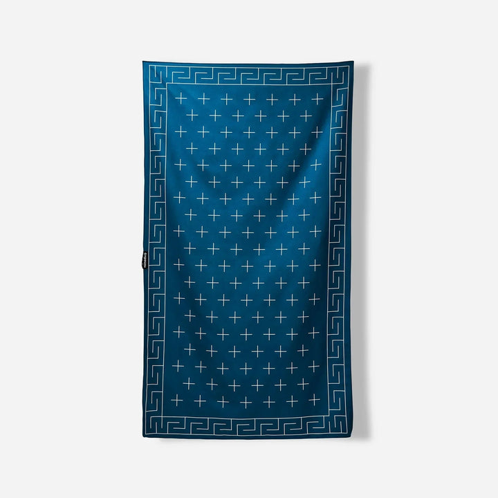 Blue beach towel with white cross pattern and Greek key border, ideal for poolside or outdoor adventures.